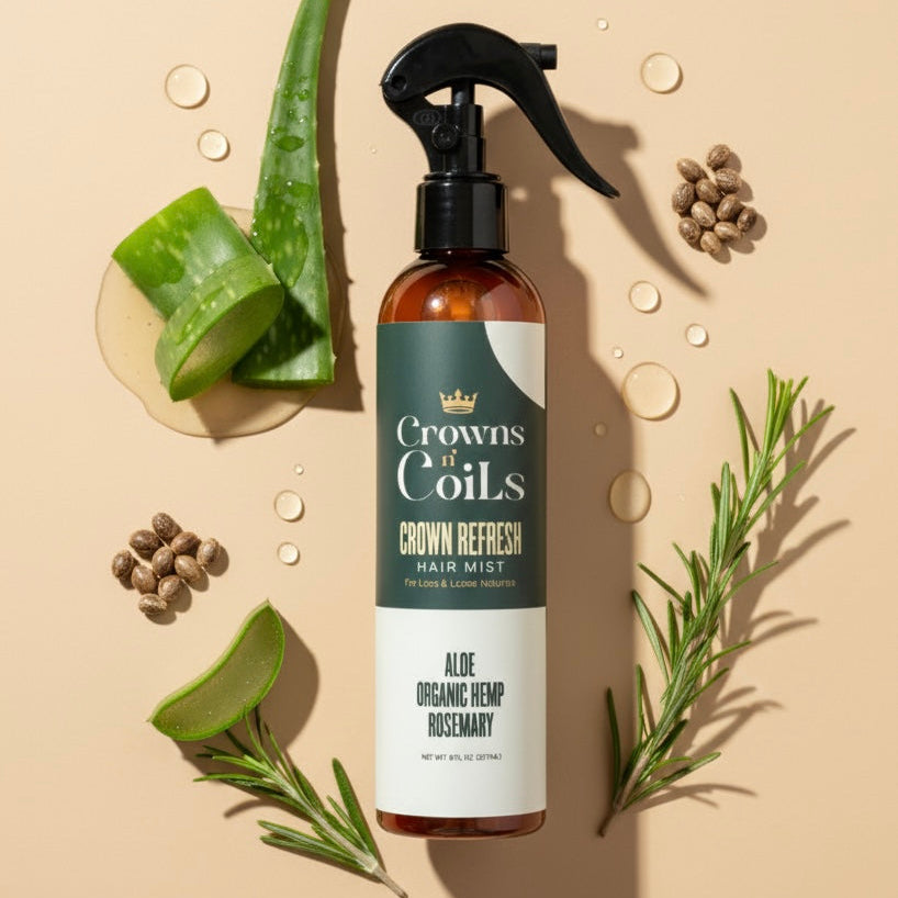Brown bottle with black sprayer labeled 'Crowns & Coils' on a beige background with green leaves and herbs.